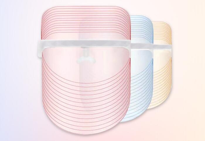 Three cylindrical containers with pink, blue, and beige lids on a light pink background